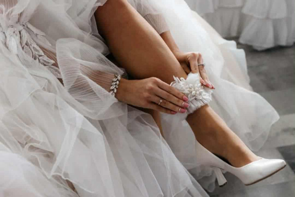 Biała podwiązka ślubna z aplikacją z koronki i perłami