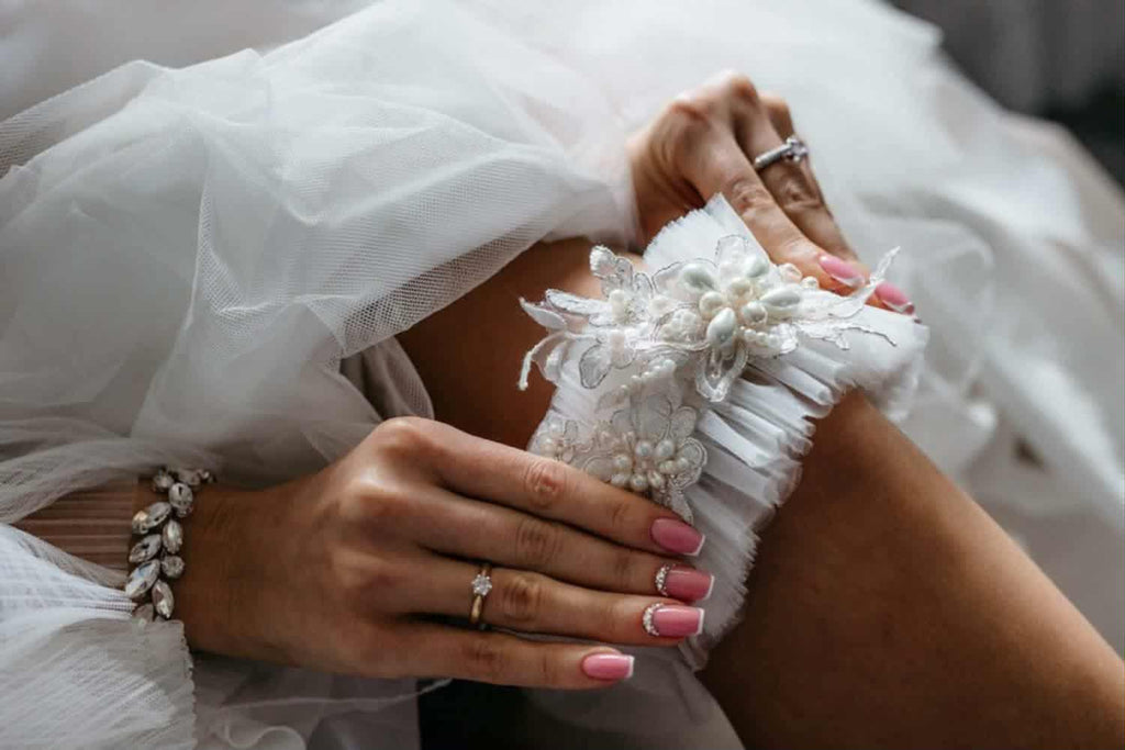 Biała podwiązka ślubna z aplikacją z koronki i perłami