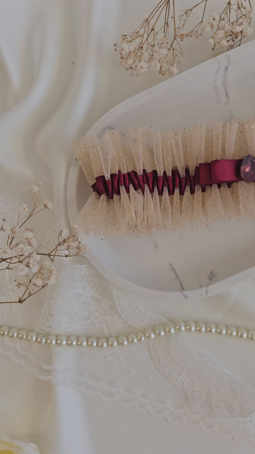 Podwiązka ślubna że złotego tiulu z bordową wstążką i kamyczkiem