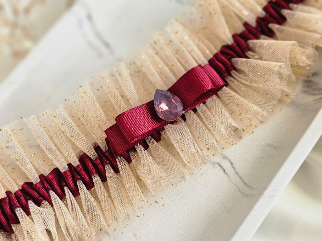 Podwiązka ślubna że złotego tiulu z bordową wstążką i kamyczkiem