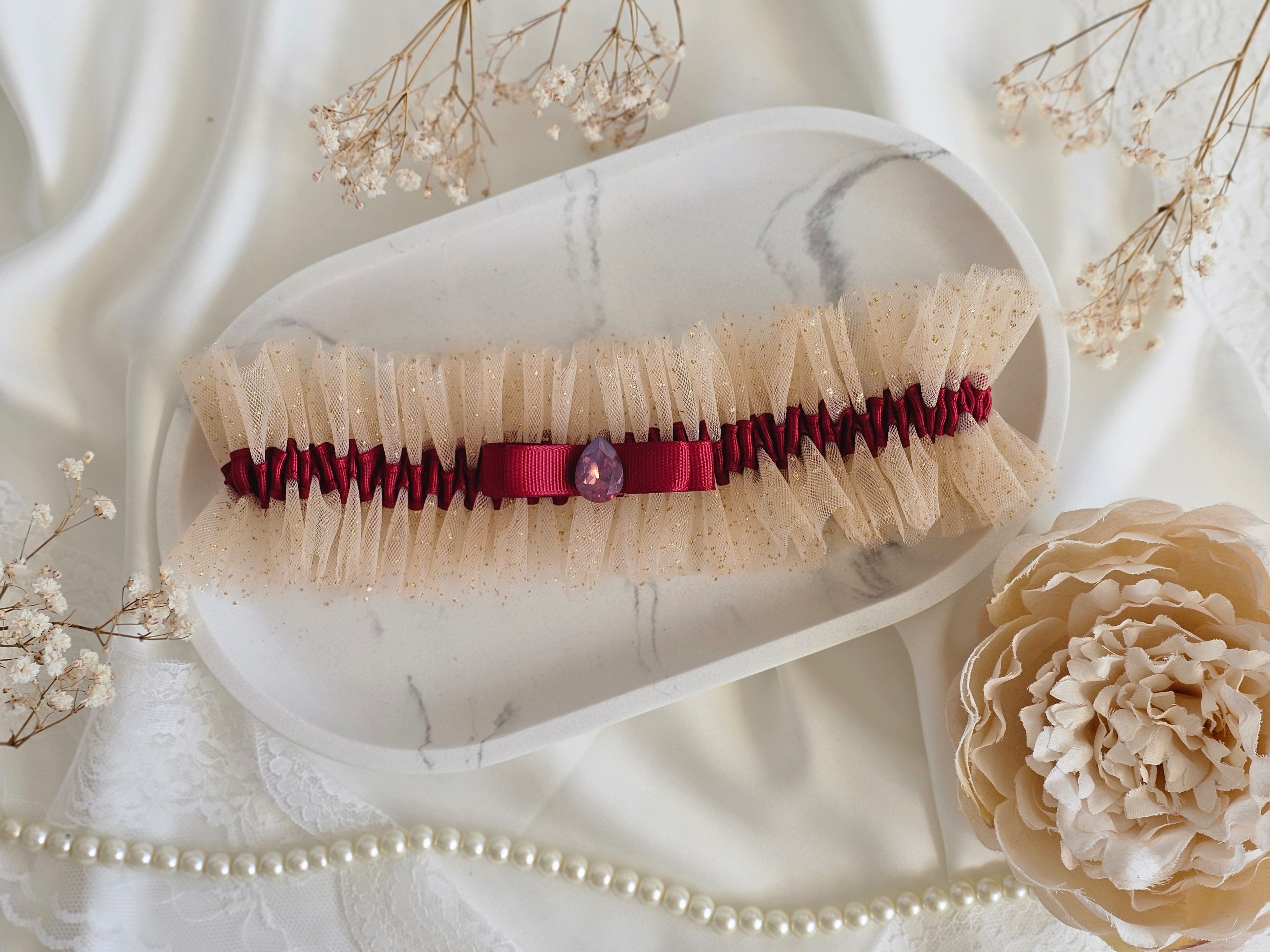 Podwiązka ślubna że złotego tiulu z bordową wstążką i kamyczkiem