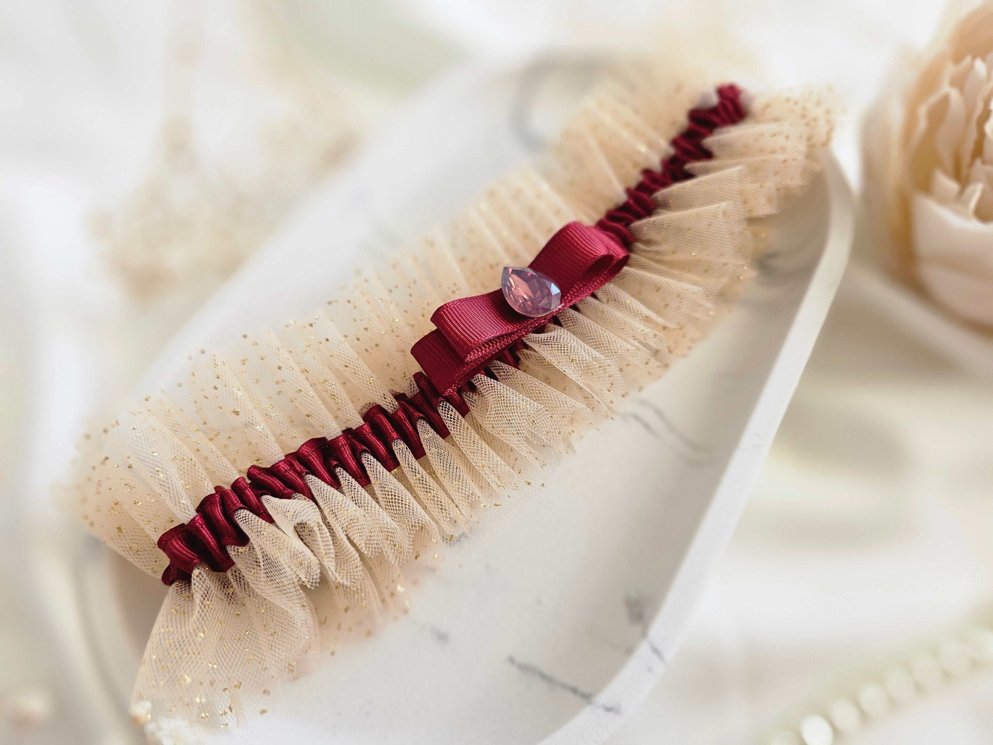 Podwiązka ślubna że złotego tiulu z bordową wstążką i kamyczkiem