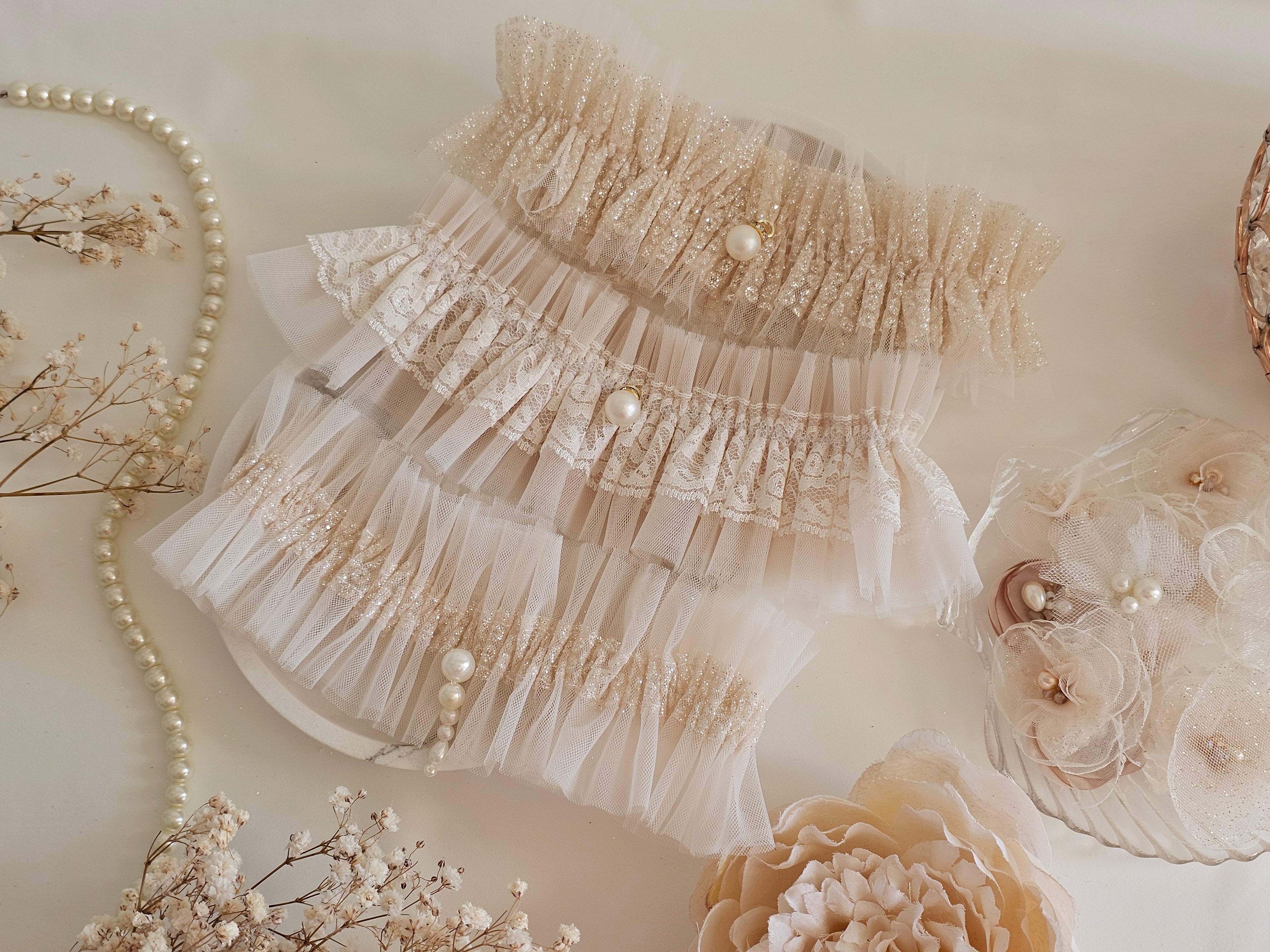 Podwiązka z najnowszej kolekcji Pearls z tiulu w kolorze kości słoniowej z dodatkiem złotego włoskiego tiulu oraz pereł.