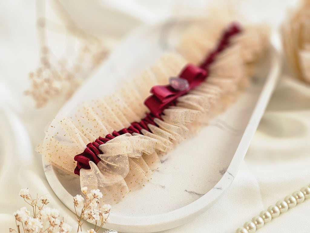 Podwiązka ślubna że złotego tiulu z bordową wstążką i kamyczkiem